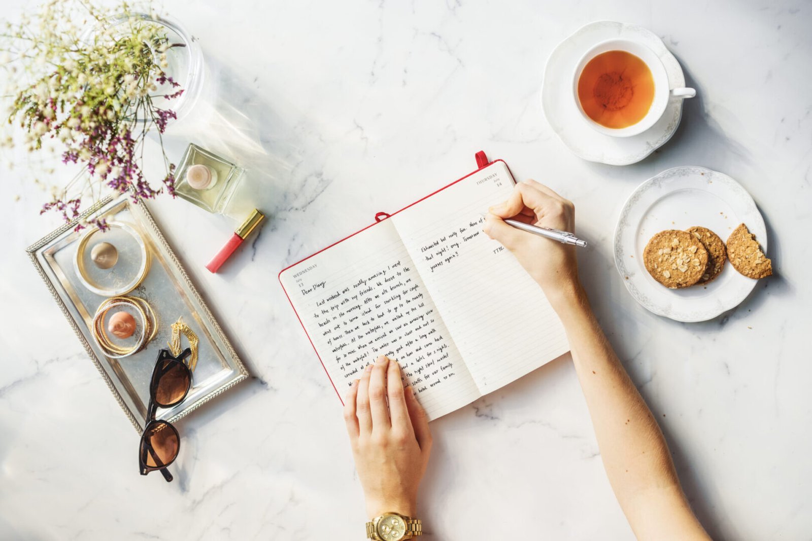 A person writing in a book on top of a table.