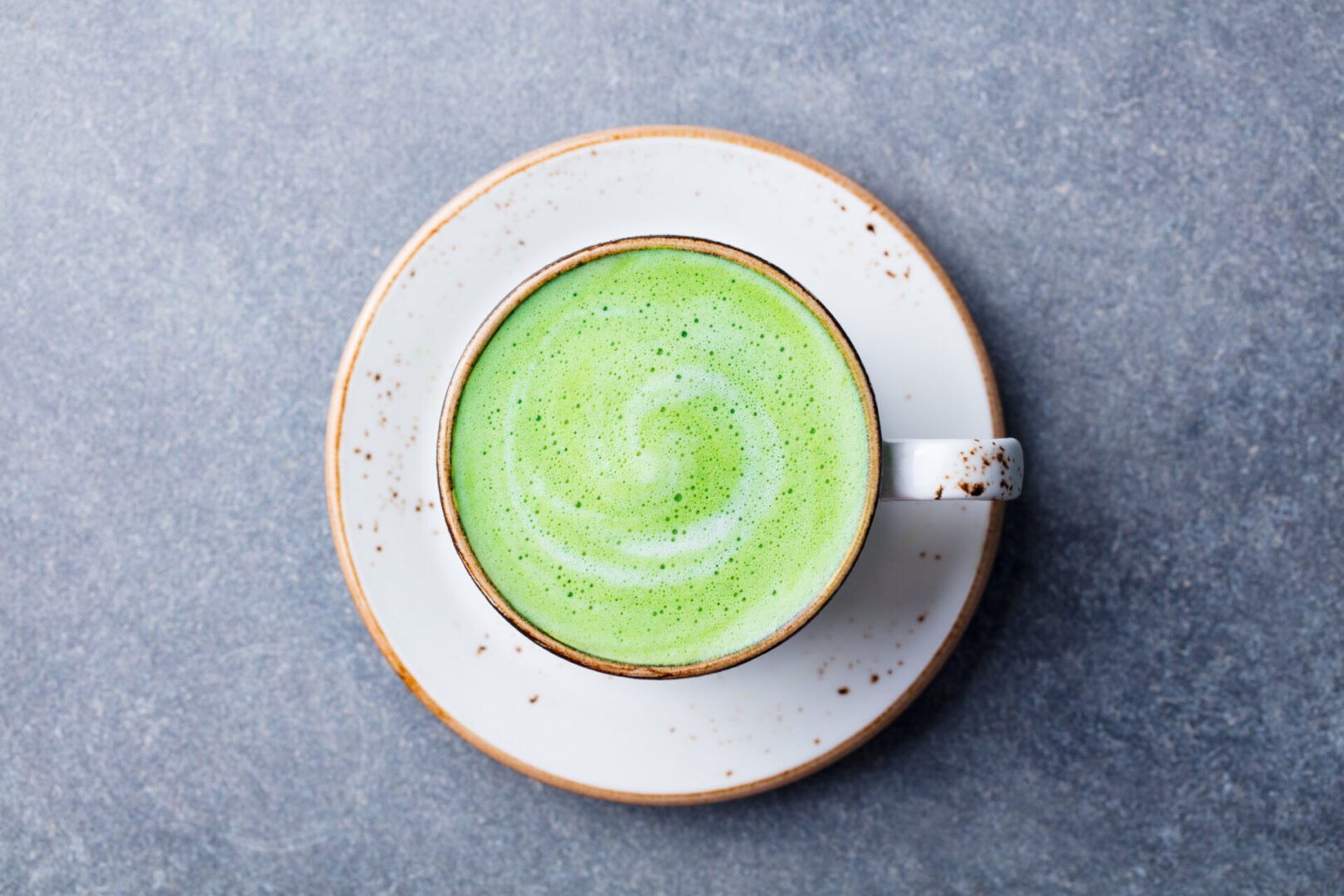 A cup of green tea on top of a white plate.